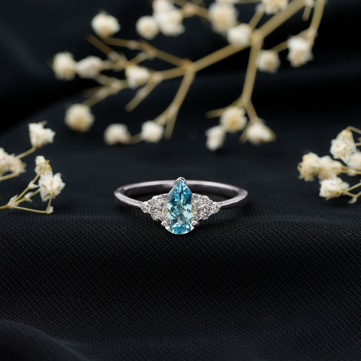 Rosec Jewels 1 Carat Aquamarine pear engagement ring with diamond trio, featuring a blue aquamarine and sparkling side stones.