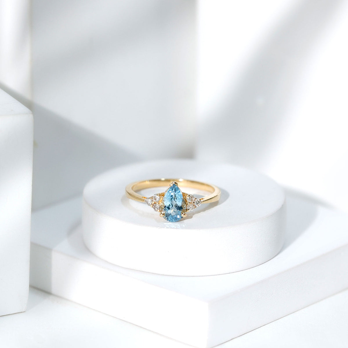Elegant 1 carat aquamarine pear-shaped engagement ring with diamond trio accents by Rosec Jewels, showcasing a sparkling gemstone setting.
