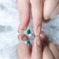 Pear-shaped emerald engagement ring with 0.6 carat AAA quality emerald and diamond accents, featuring a silver band.