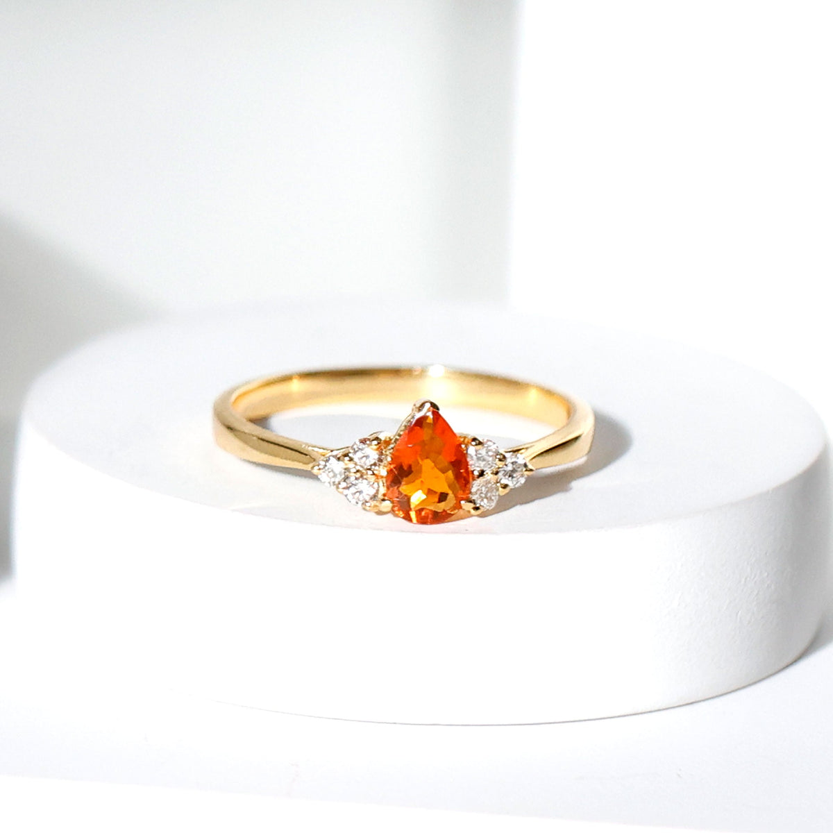 Pear-shaped fire opal engagement ring with diamond trio set in a Rosec Jewels ring, showcasing vibrant orange and white gemstones.