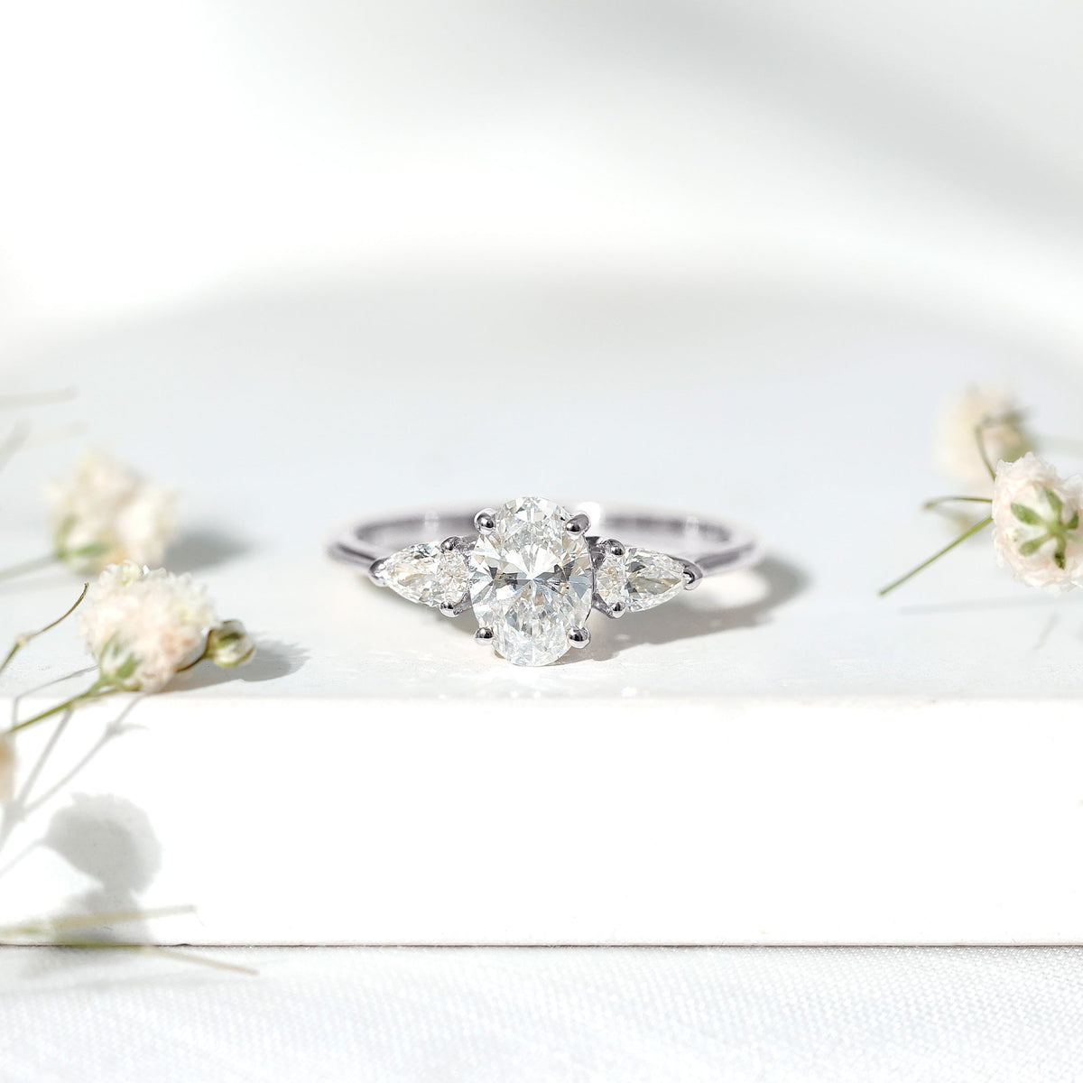 Oval and pear cut moissanite three stone engagement ring by Rosec Jewels featuring sparkling gemstones on a silver band