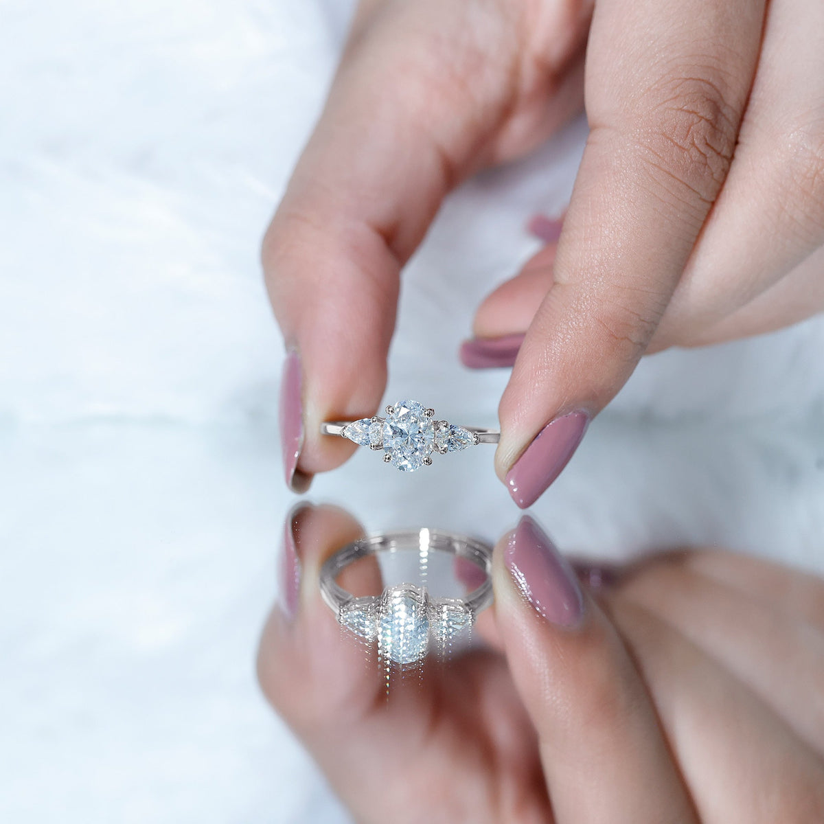 Oval and pear cut moissanite three-stone engagement ring from Rosec Jewels featuring a delicate gold band and sparkling gemstones.