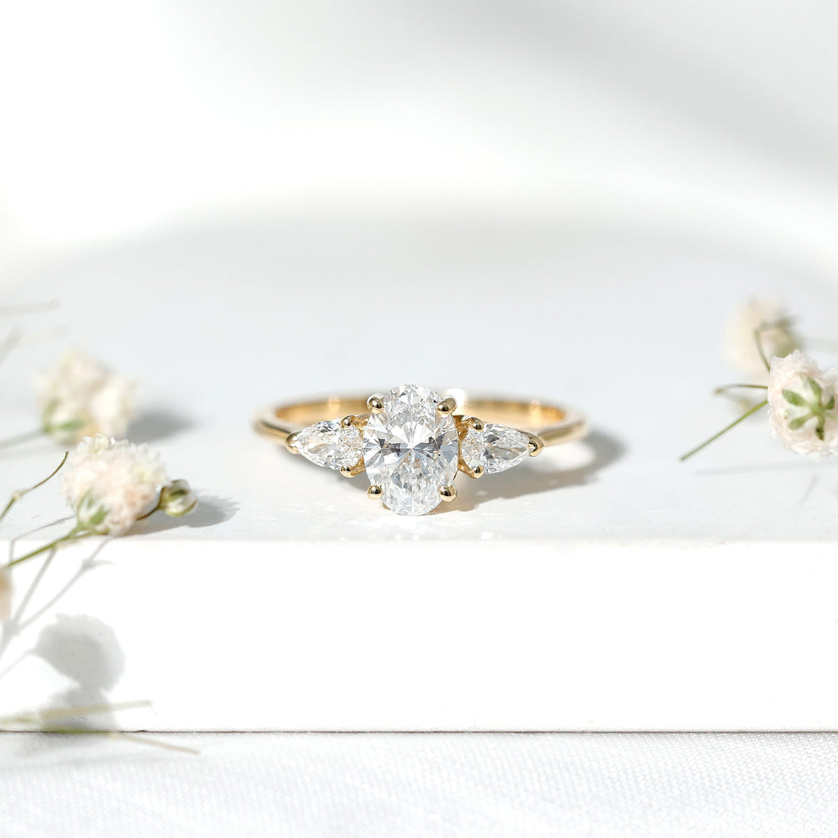 Oval and pear cut moissanite three stone engagement ring featuring a rose gold band from Rosec Jewels.