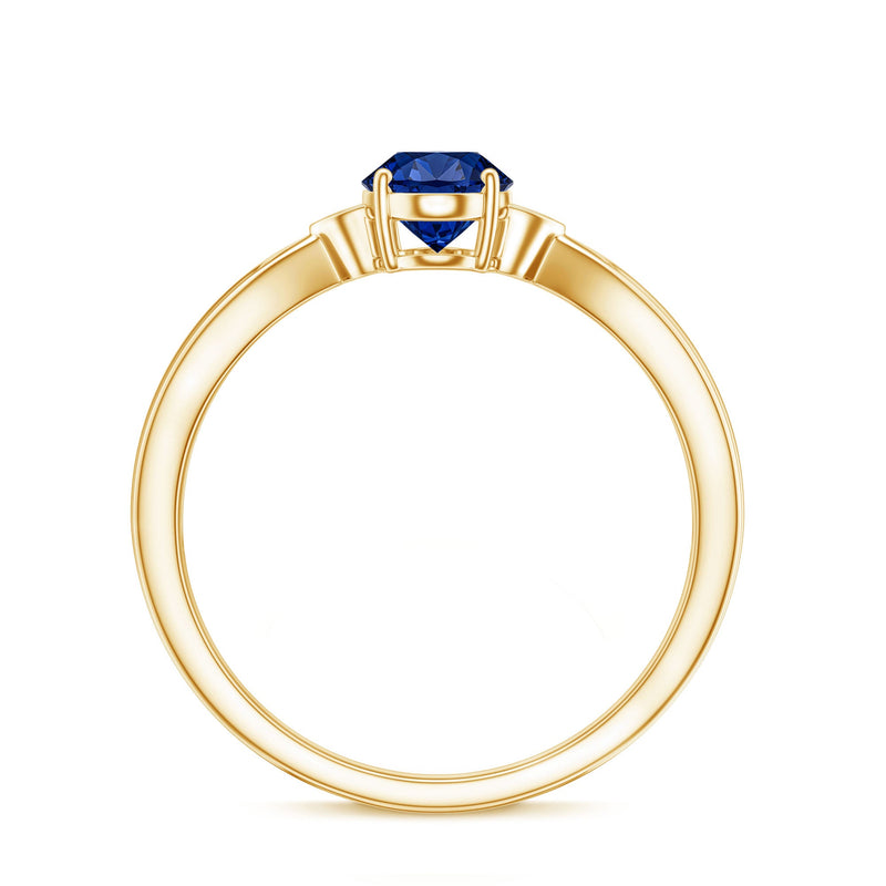 Oval lab-grown blue sapphire solitaire engagement ring with diamond accent, showcasing a polished platinum band and sparkling gemstone.