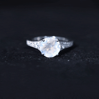 Rosec Jewels moonstone engagement ring with diamond side stones, featuring a polished silver band and a central glowing moonstone.