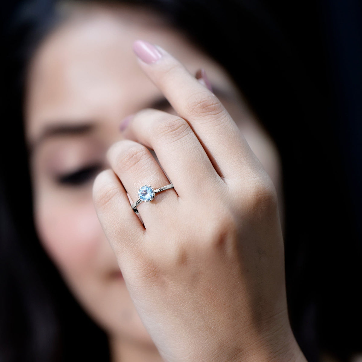 Round cut aquamarine solitaire engagement ring with a 0.8 carat gemstone in a silver setting, featuring a classic and elegant design.