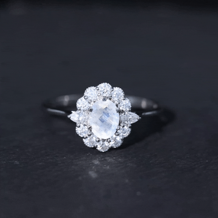 Oval-shaped moonstone engagement ring with moissanite accents, featuring a yellow gold band from Rosec Jewels.