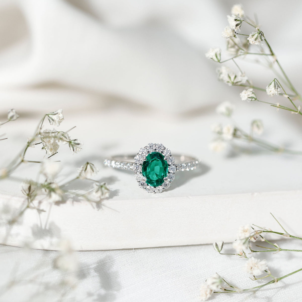 Oval lab-grown emerald halo engagement ring with diamond accents from Rosec Jewels, showcasing the detailed gemstone setting.