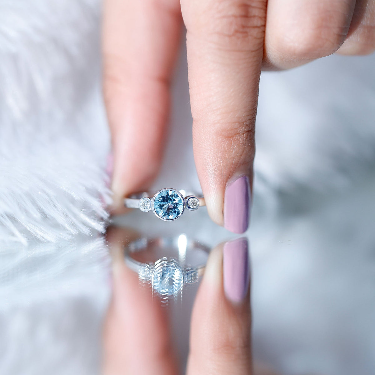 Bezel set aquamarine and diamond engagement ring from Rosec Jewels featuring a central aquamarine gemstone and sparkling diamonds.