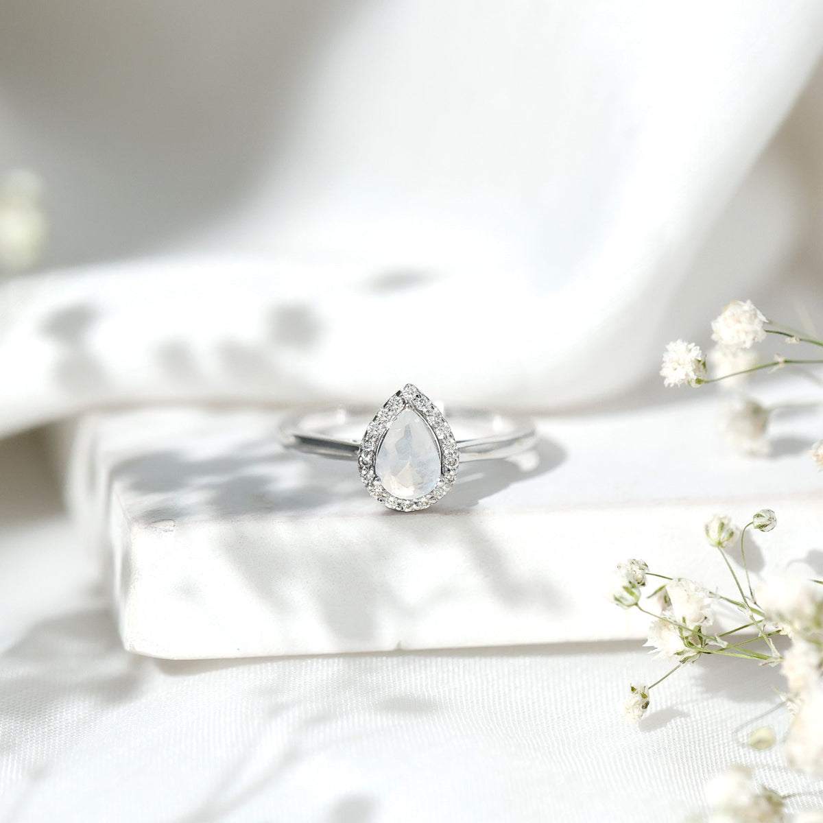 Pear-shaped moonstone halo engagement ring with diamond accents by Rosec Jewels, showcasing a detailed, elegant ring design.