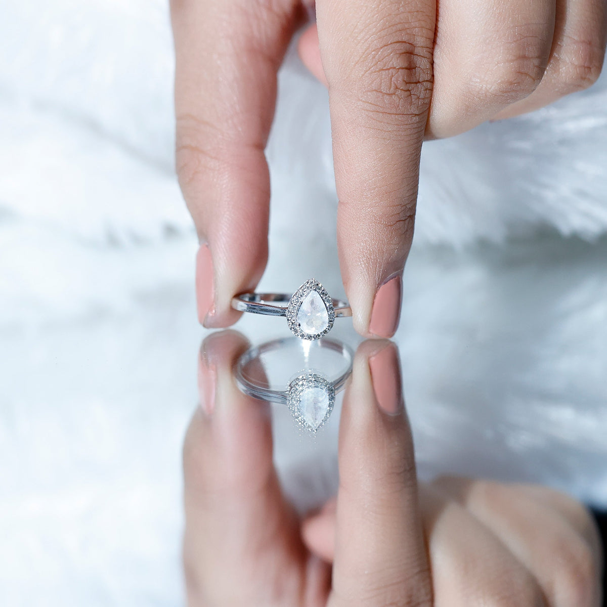 Pear-shaped moonstone halo engagement ring with diamond accents, crafted by Rosec Jewels, showcasing a sparkling gemstone and intricate design.