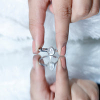 Pear-shaped moonstone halo engagement ring with diamond accents, crafted by Rosec Jewels, showcasing a sparkling gemstone and intricate design.