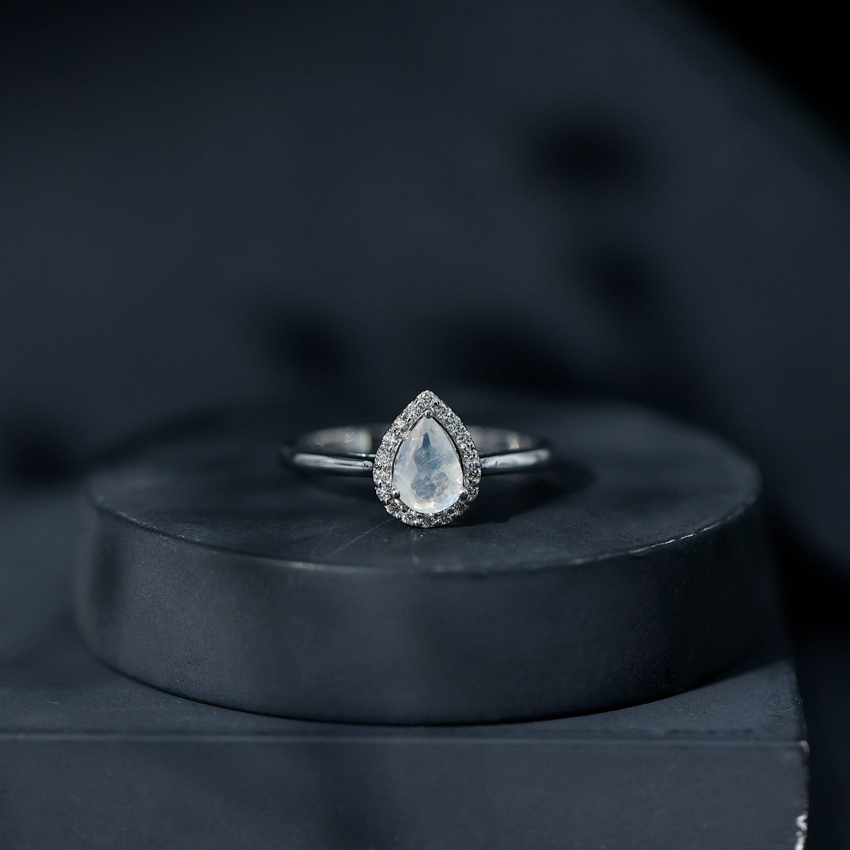 Pear-shaped moonstone halo engagement ring with diamond accents, featuring a rose gold band from Rosec Jewels.
