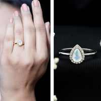 Pear-shaped moonstone halo engagement ring with diamond accents, featuring a rose gold band and intricate detailing from Rosec Jewels.