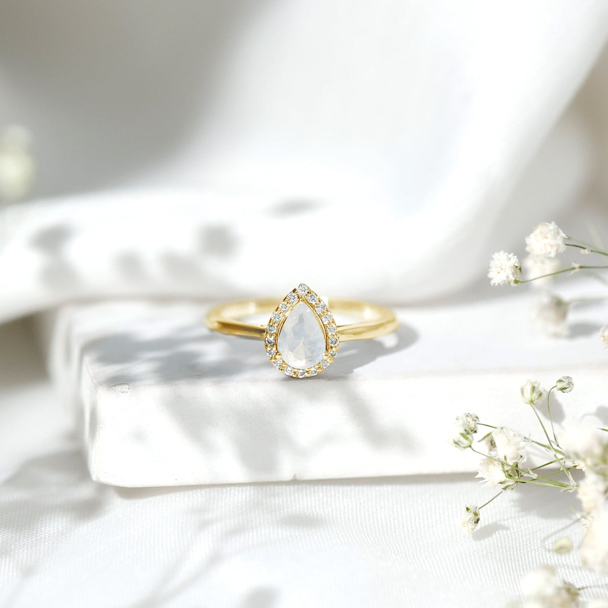 Pear-shaped moonstone halo engagement ring with diamond accents by Rosec Jewels, showcasing the elegant jewelry design.