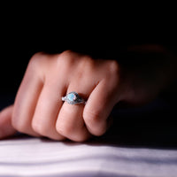 Genuine Ethiopian opal antique-style engagement ring with diamond halo, featuring intricate metalwork and a stunning central stone.