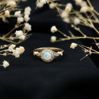 Genuine Ethiopian opal engagement ring with antique look and diamond halo, featuring intricate detailing and a silver band.