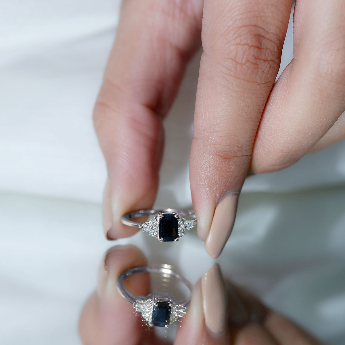Emerald cut black diamond solitaire ring with diamond trio accents by Rosec Jewels, showcasing the ring on a neutral background.