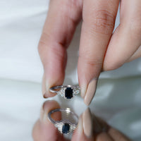 Emerald cut black diamond solitaire ring with diamond trio accents by Rosec Jewels, showcasing the ring on a neutral background.
