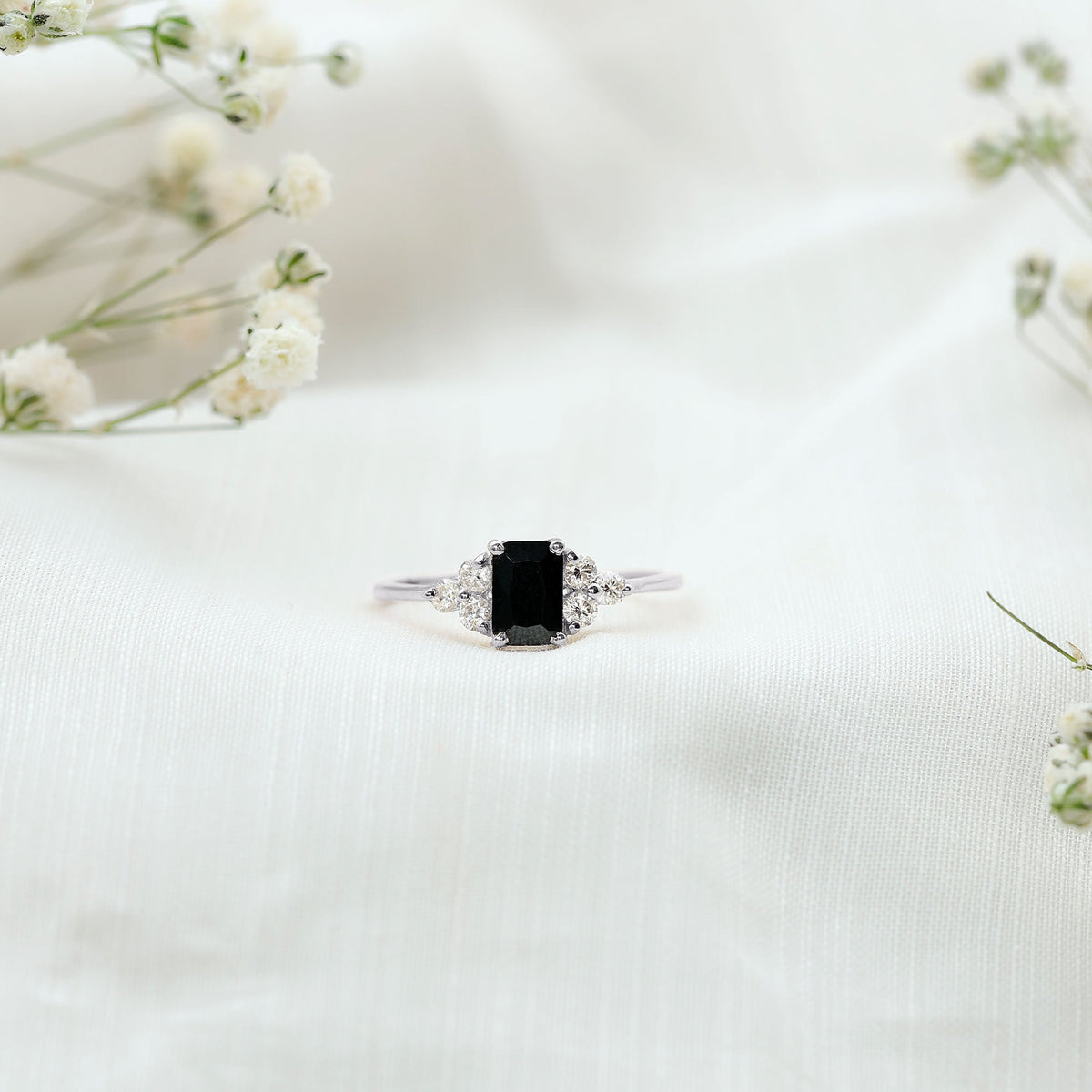 Emerald cut black diamond solitaire ring with diamond trio accents by Rosec Jewels, showcasing a sleek black gemstone setting.