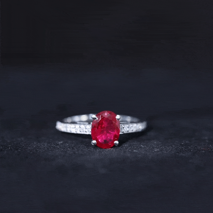 Yellow gold 1.5 carat lab-grown ruby oval engagement ring with diamond side stones and intricate detailing.