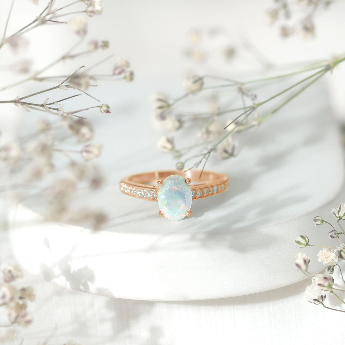 Natural 1.2 carat Ethiopian opal oval engagement ring with diamond side stones, set in a rose gold band.
