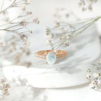 Natural 1.2 carat Ethiopian opal oval engagement ring with diamond side stones, set in a rose gold band.