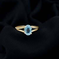 Genuine oval aquamarine solitaire engagement ring with a split shank design from Rosec Jewels, showcasing a sparkling blue gemstone.