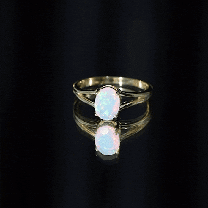 Oval Ethiopian rainbow opal engagement ring with split shank design, featuring a 1.2 carat genuine gemstone and gold band.