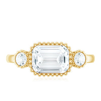 Emerald cut moissanite 3-stone engagement ring in east-west style, featuring sparkling stones set in a rose gold band.