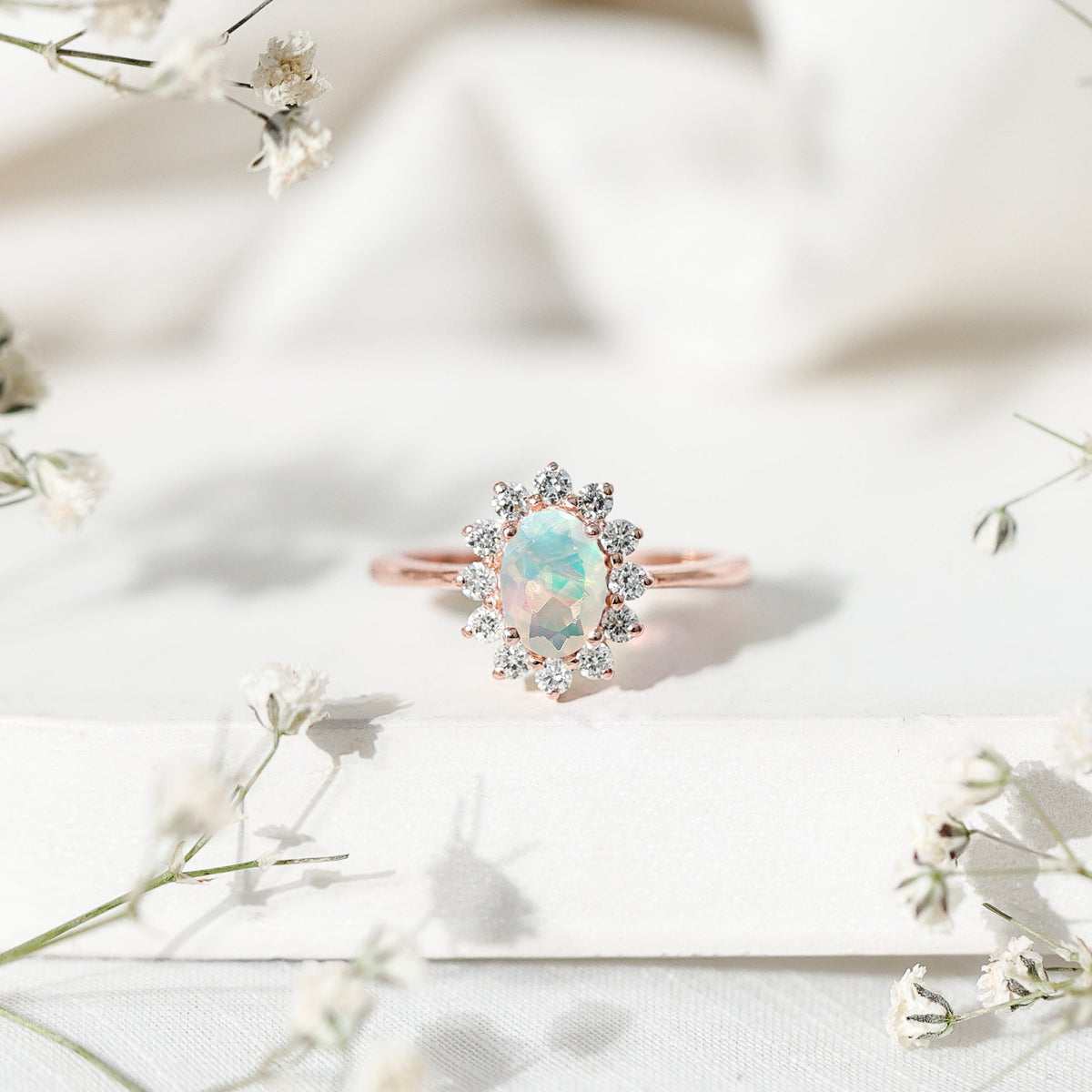 Oval Ethiopian opal engagement ring with diamond halo, featuring a rose gold setting and intricate detailing.