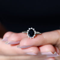 Oval cut black onyx engagement ring with diamond halo, set in a silver band, by Rosec Jewels.
