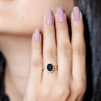 Oval cut black onyx engagement ring with diamond halo setting, featuring a rose gold band and intricate detailing by Rosec Jewels.