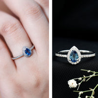 Natural half carat blue sapphire teardrop engagement ring with diamond halo, featuring a rose gold band and intricate detailing.