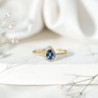 Natural half carat blue sapphire teardrop engagement ring with diamond halo, featuring rose gold band, by Rosec Jewels.