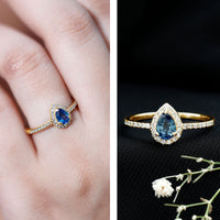 Natural half carat blue sapphire teardrop engagement ring with diamond halo, featuring a delicate silver band and intricate detailing.