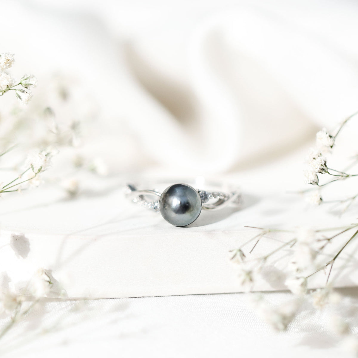 Tahitian pearl and diamond crossover engagement ring by Rosec Jewels featuring a pearl and sparkling diamonds on a gold band.