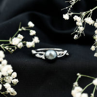 Tahitian pearl and diamond crossover engagement ring by Rosec Jewels featuring a central pearl with diamond accents on a gold band.