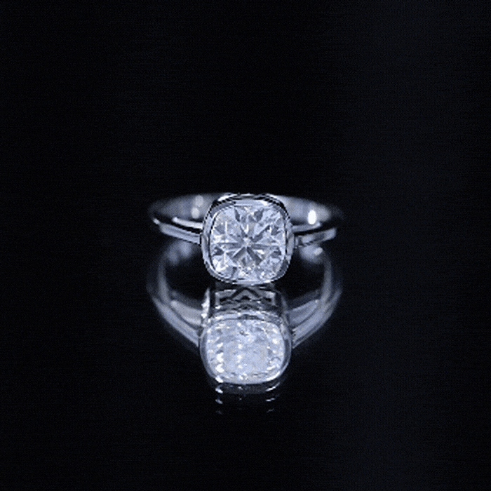 Yellow gold bezel set cushion cut moissanite solitaire engagement ring by Rosec Jewels featuring a prominent central gemstone and elegant band.