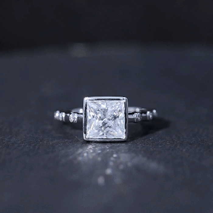 Yellow gold bezel set moissanite princess cut engagement ring with spaced accent diamonds by Rosec Jewels.