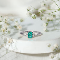 Emerald cut emerald engagement ring with diamond trio accents, featuring a rose gold band from Rosec Jewels.