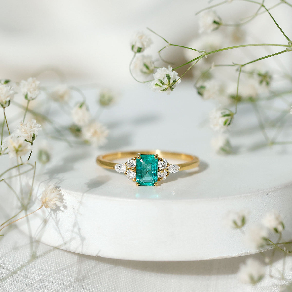 Emerald cut emerald engagement ring with diamond trio accents from Rosec Jewels featuring a sleek gold band.