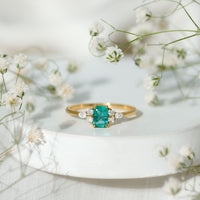 Emerald cut emerald engagement ring with diamond trio accents from Rosec Jewels featuring a sleek gold band.