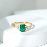 Emerald cut emerald engagement ring with diamond trio accents from Rosec Jewels, showcasing a stunning green gemstone and sparkling side diamonds.