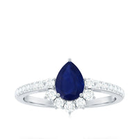 Pear-shaped blue sapphire and diamond half halo engagement ring with 0.5 carat center stone, featuring rose gold and intricate detailing.