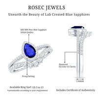 Blue sapphire and diamond pear-shaped engagement ring set by Rosec Jewels with intricate band design and sparkling gemstones.