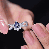Pear-shaped blue sapphire engagement ring with diamond crossover design by Rosec Jewels, showcasing a sparkling blue sapphire and diamond accents.