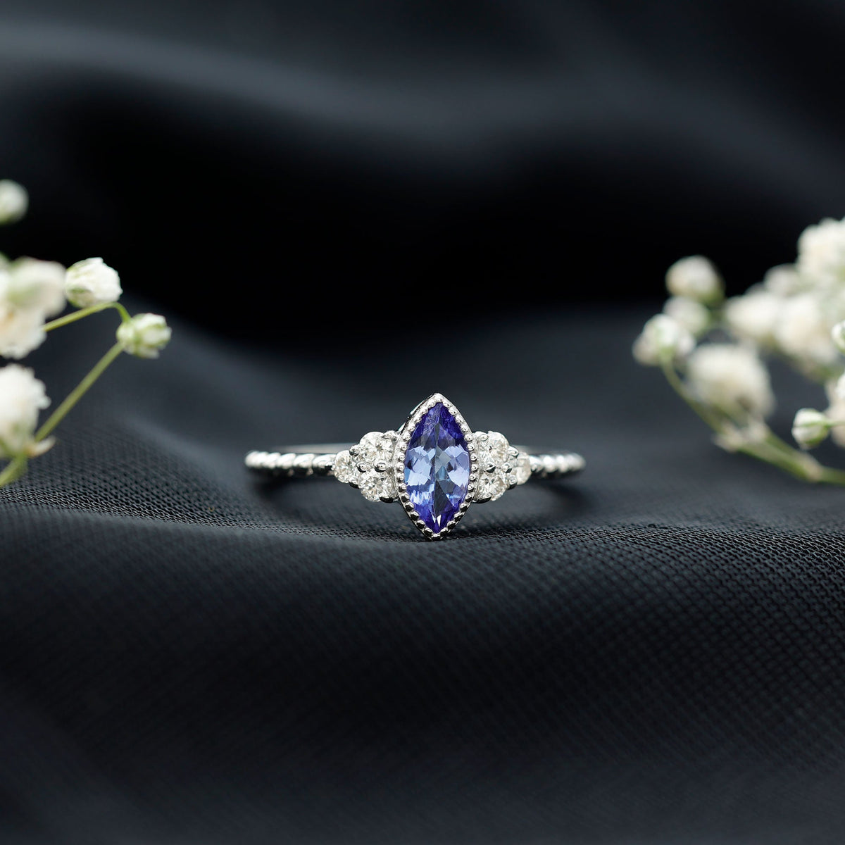 Vintage-style marquise tanzanite promise ring with diamond trio accents from Rosec Jewels, showcasing intricate design and sparkling gemstones.