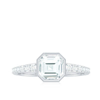 Asscher cut moissanite solitaire engagement ring in bezel setting with a silver band, showcasing elegant jewelry craftsmanship.