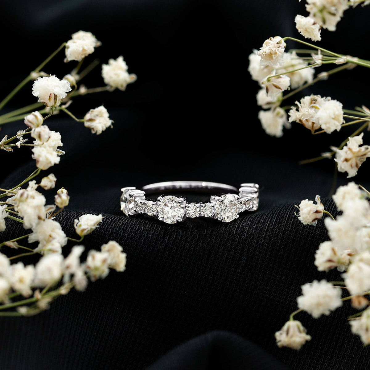 Round moissanite half eternity wedding band by Rosec Jewels featuring sparkling stones set in a polished silver ring.